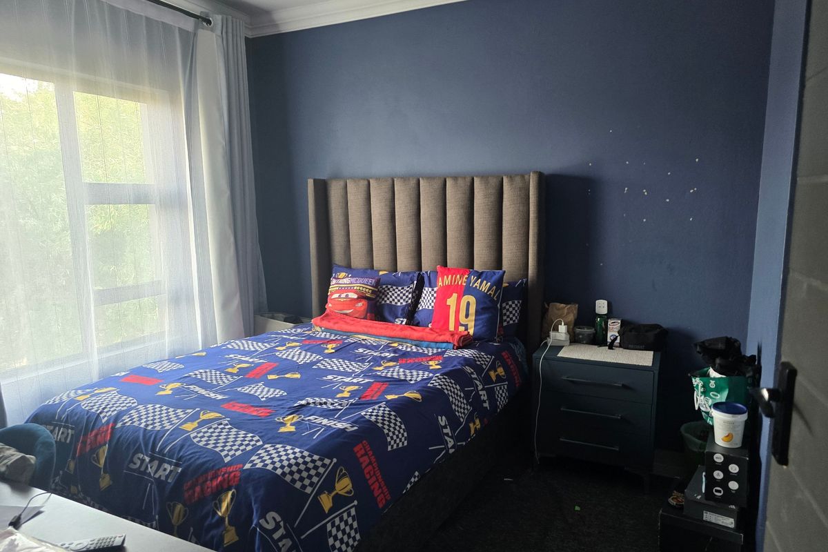 A bedroom featuring dark blue accent walls, a large window with natural light, and decorative cove cornicing.