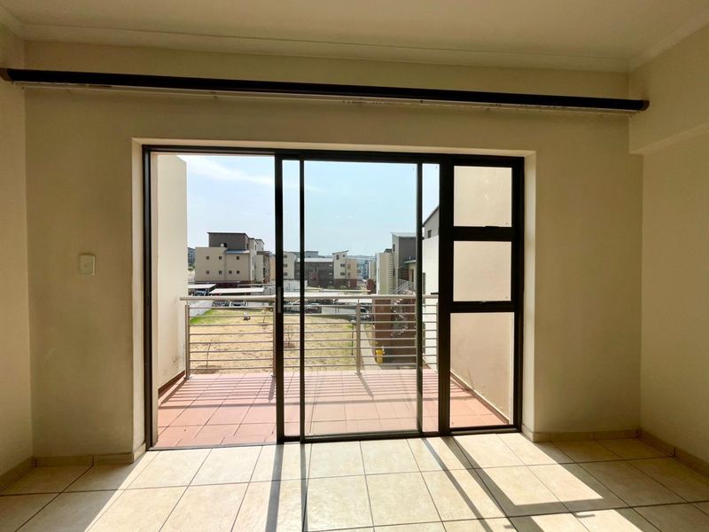 Bright and empty living area featuring large sliding glass doors that open onto a private balcony with neighborhood views.