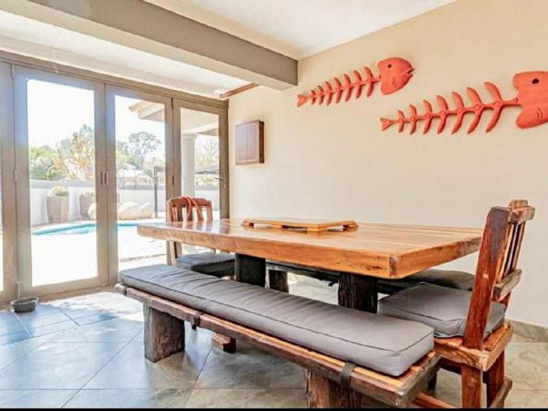 Dining area featuring tiled flooring and large sliding glass doors providing direct access to the outdoor pool area.