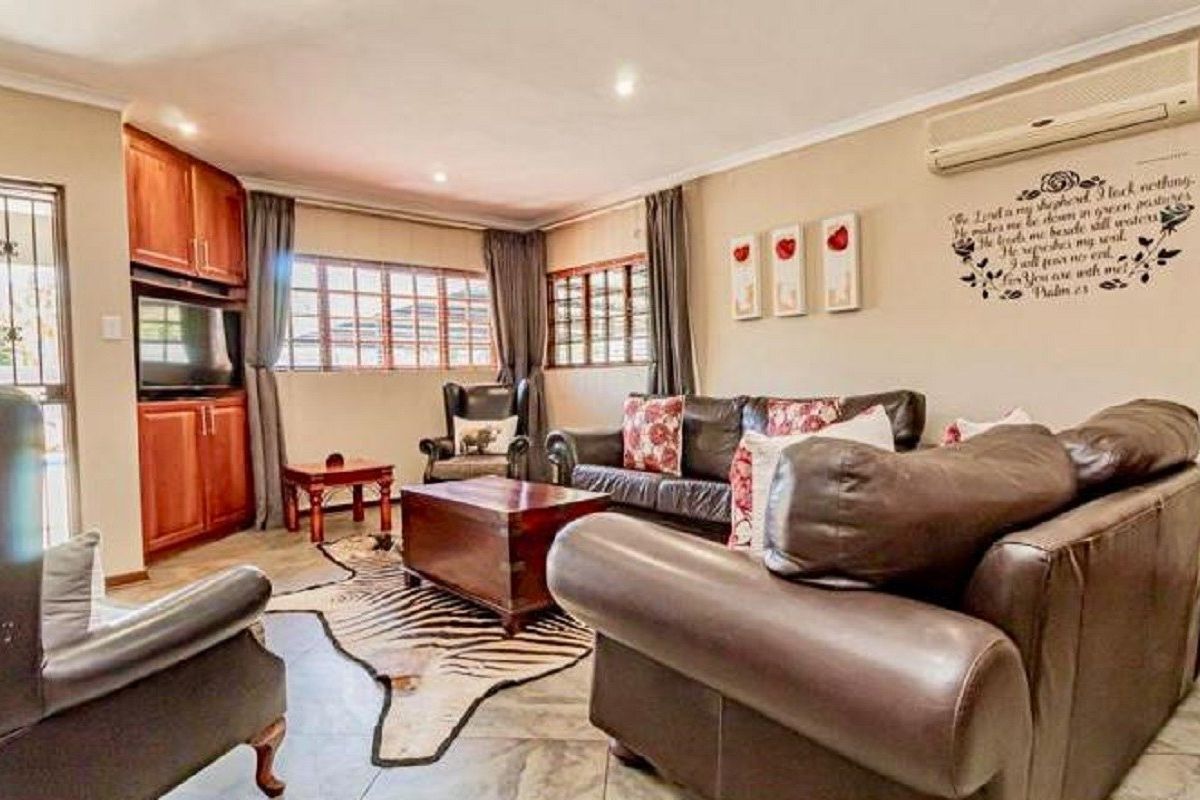 A comfortable living room featuring tiled flooring, built-in wooden cabinetry, and a wall-mounted air conditioning unit.
