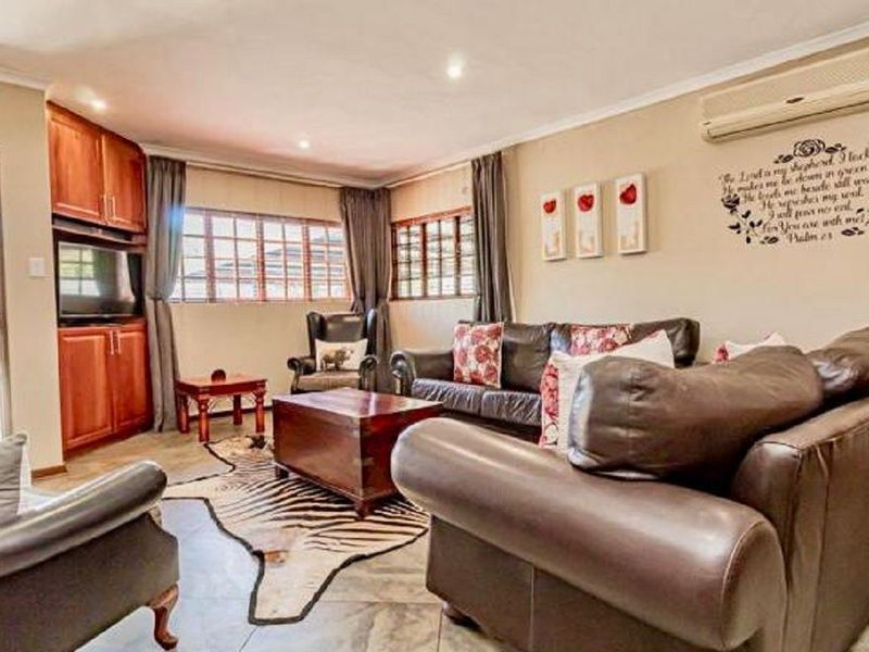 A comfortable living room featuring tiled flooring, built-in wooden cabinetry, and a wall-mounted air conditioning unit.