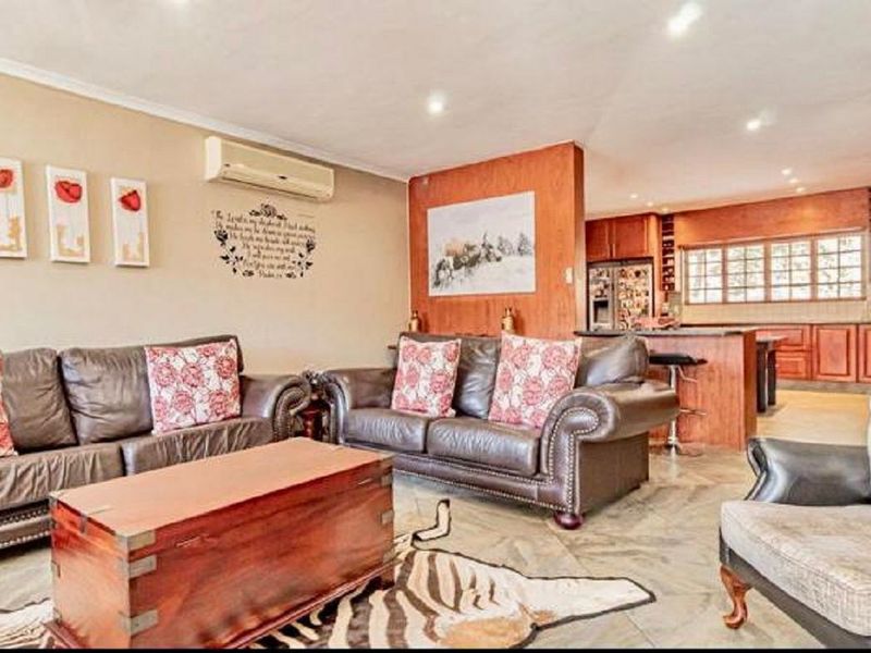 Open-plan living area featuring tiled floors, recessed lighting, and a connected kitchen with wooden cabinetry and an island bench.