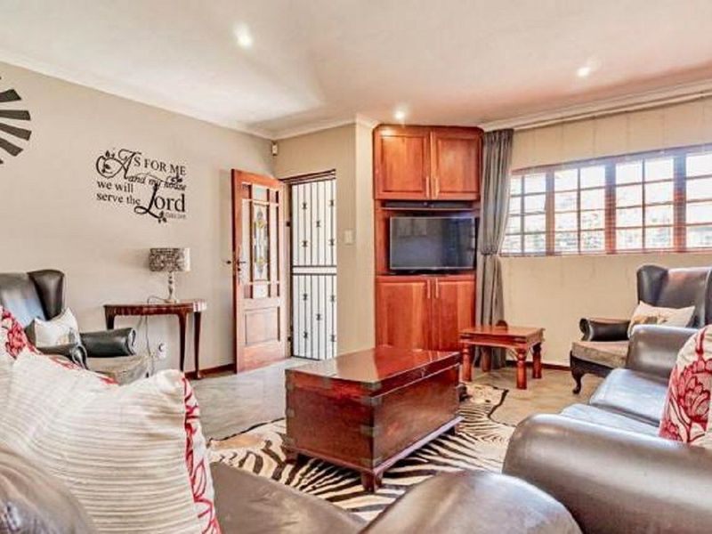 A comfortable living room featuring built-in wooden cabinetry, recessed lighting, and a secure entrance door with an integrated security gate.