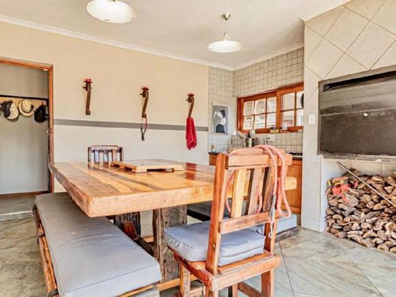 Covered patio area featuring a built-in braai, tiled flooring, and direct access to the interior, suitable for outdoor dining and entertainment.