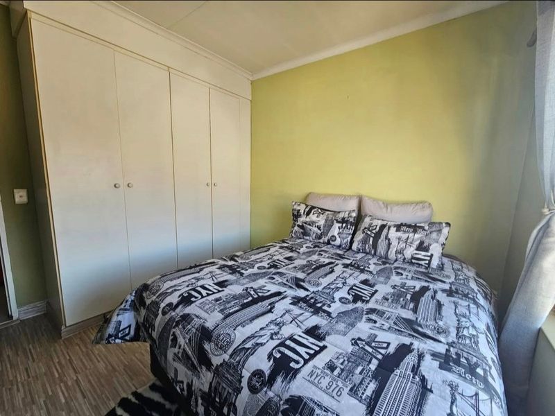 A bedroom featuring built-in wardrobes, laminate flooring, and a neutral color scheme, offering a functional and comfortable living space.