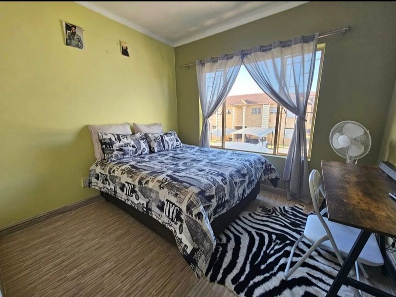 A bedroom featuring laminate flooring and a large window providing natural light and exterior views.