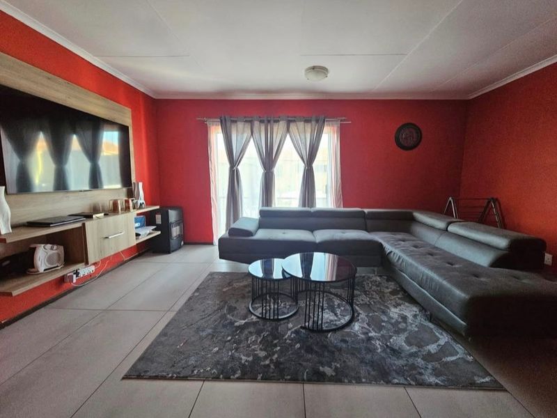 Spacious living room featuring tiled flooring, a built-in media console, and a sliding glass door providing access to the exterior.