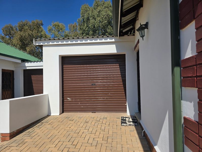A view of the townhouse garage featuring a brown roll-up door and a brick-paved driveway entrance.