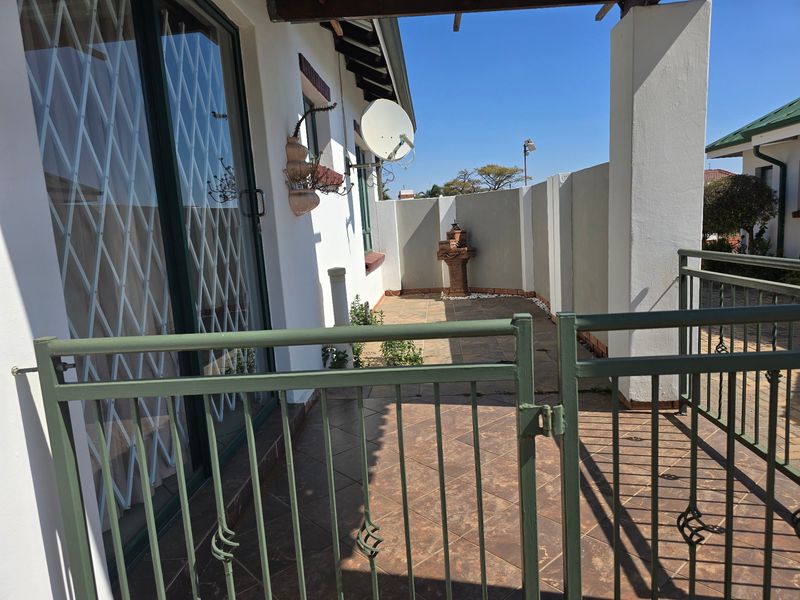 A private outdoor patio area featuring tiled flooring, a decorative water feature, and secure metal gate access to the main living space.