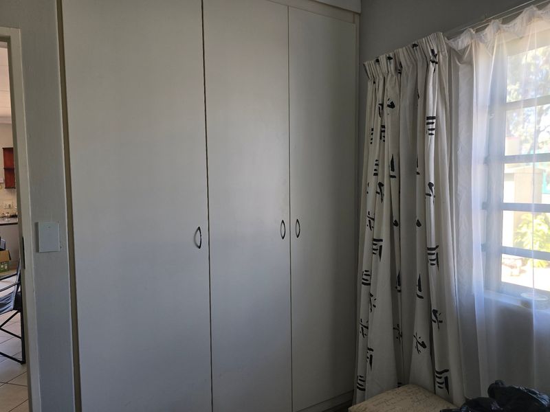 A bedroom featuring built-in cupboards and a window with natural light.