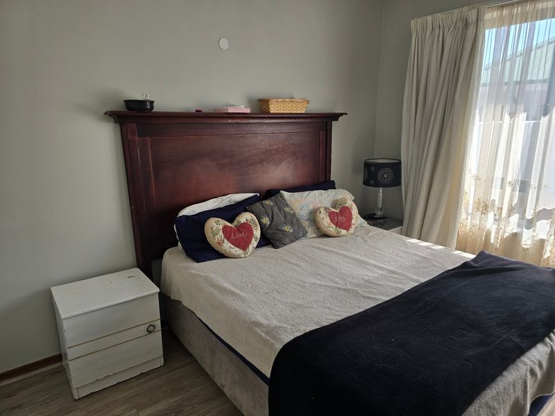 A bedroom featuring laminate flooring and window treatments, providing a functional space with neutral wall tones.