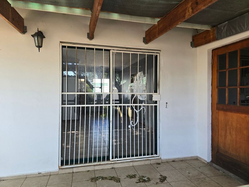 Covered patio area featuring tiled flooring, a timber pergola structure, and secure sliding door access to the interior living space.
