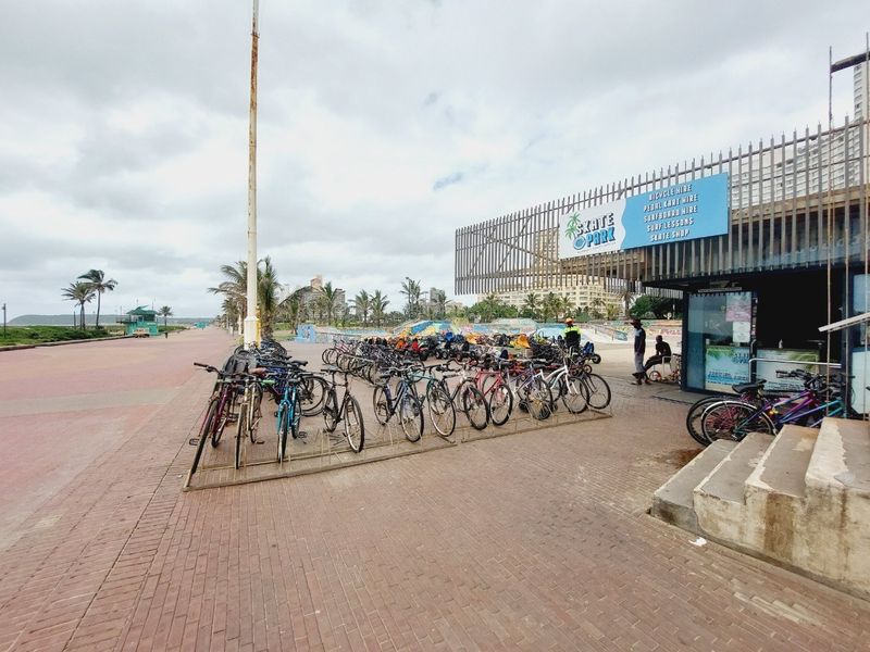 Exterior view of a beachfront commercial facility featuring paved walkways and metal security structures near the promenade.
