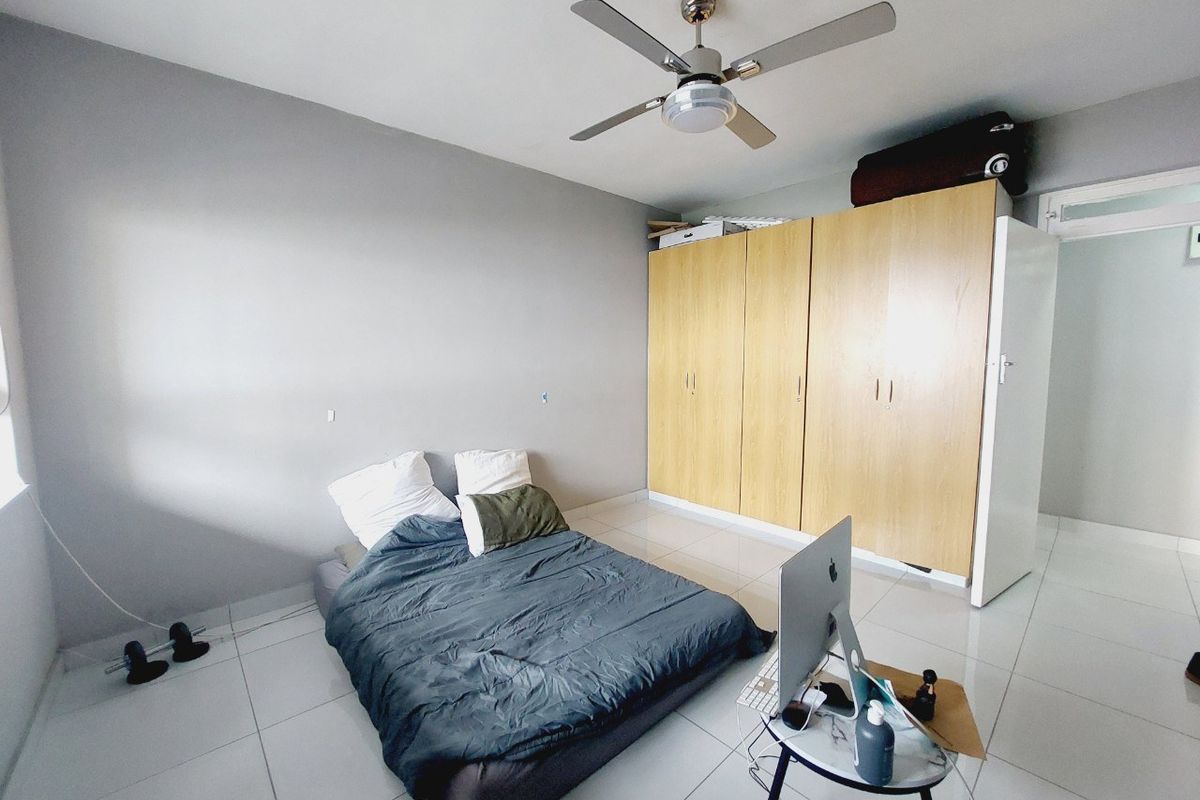 A bedroom featuring tiled flooring, a ceiling fan, and a large built-in wooden wardrobe providing ample storage space.