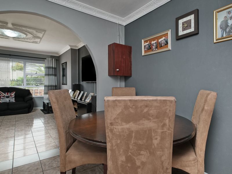 Open plan living and dining area featuring tiled flooring, decorative ceiling cornices, and a classic archway connecting the two spaces.