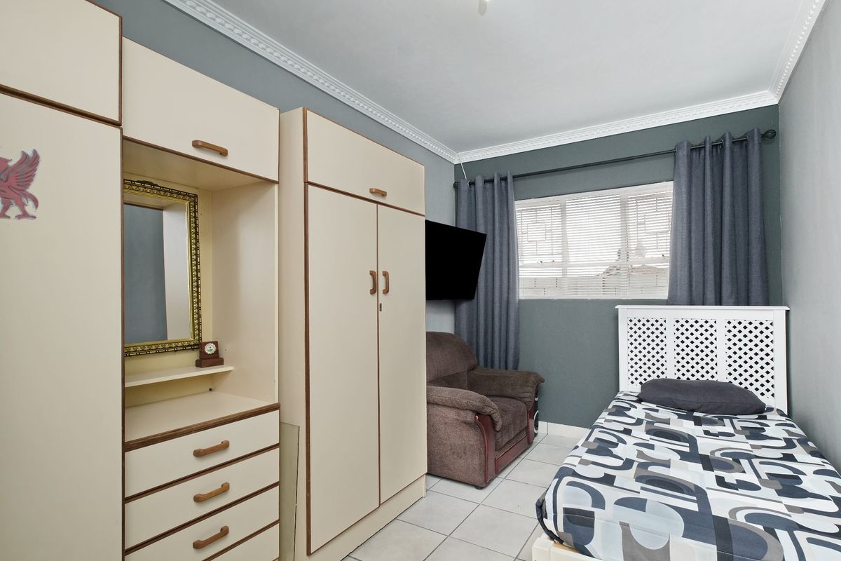 A functional bedroom featuring built-in cupboards, tiled flooring, and decorative crown molding, providing a practical and well-defined living space.