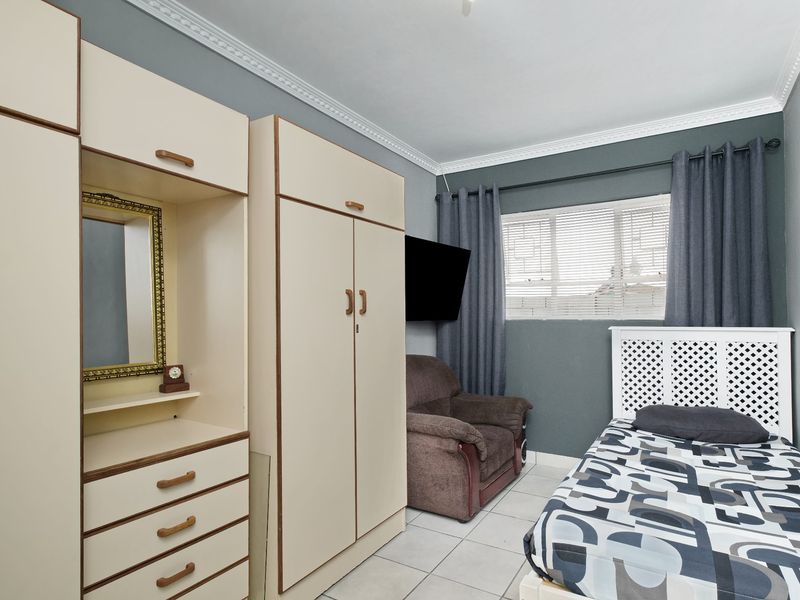 A functional bedroom featuring built-in cupboards, tiled flooring, and decorative crown molding, providing a practical and well-defined living space.