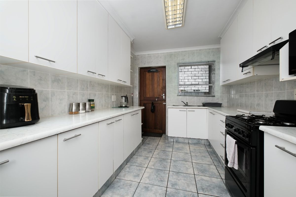 A functional kitchen featuring white cabinetry, tiled backsplash, gas stove, and tiled flooring, offering a clean and practical workspace.