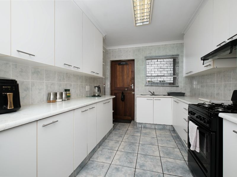 A functional kitchen featuring white cabinetry, tiled backsplash, gas stove, and tiled flooring, offering a clean and practical workspace.