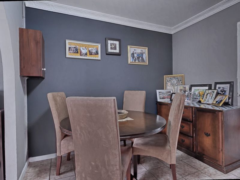 A dining room featuring dark grey accent walls, decorative crown molding, and tiled flooring, providing a functional space for meals.