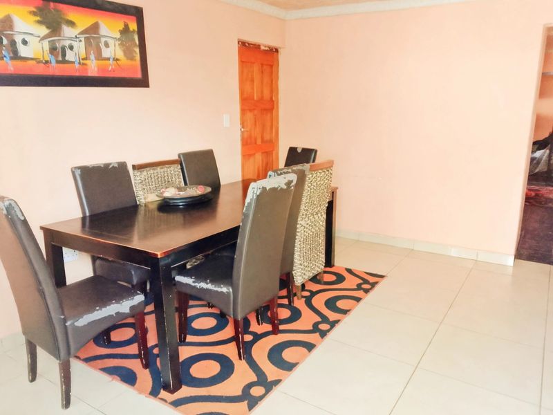 A dining area featuring tiled flooring and a wooden door, providing a functional space for meals.