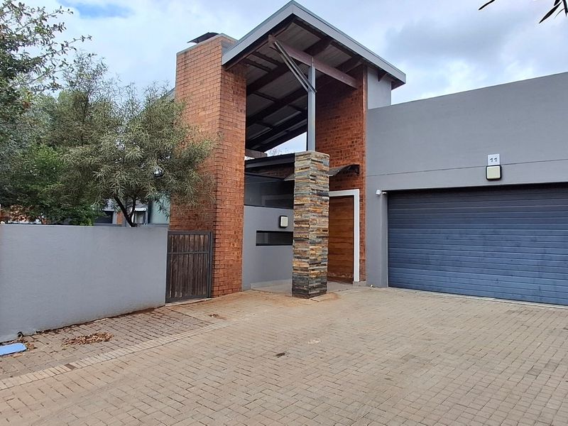 Modern townhouse exterior featuring a brick and stone facade, paved driveway, and a secure double garage.