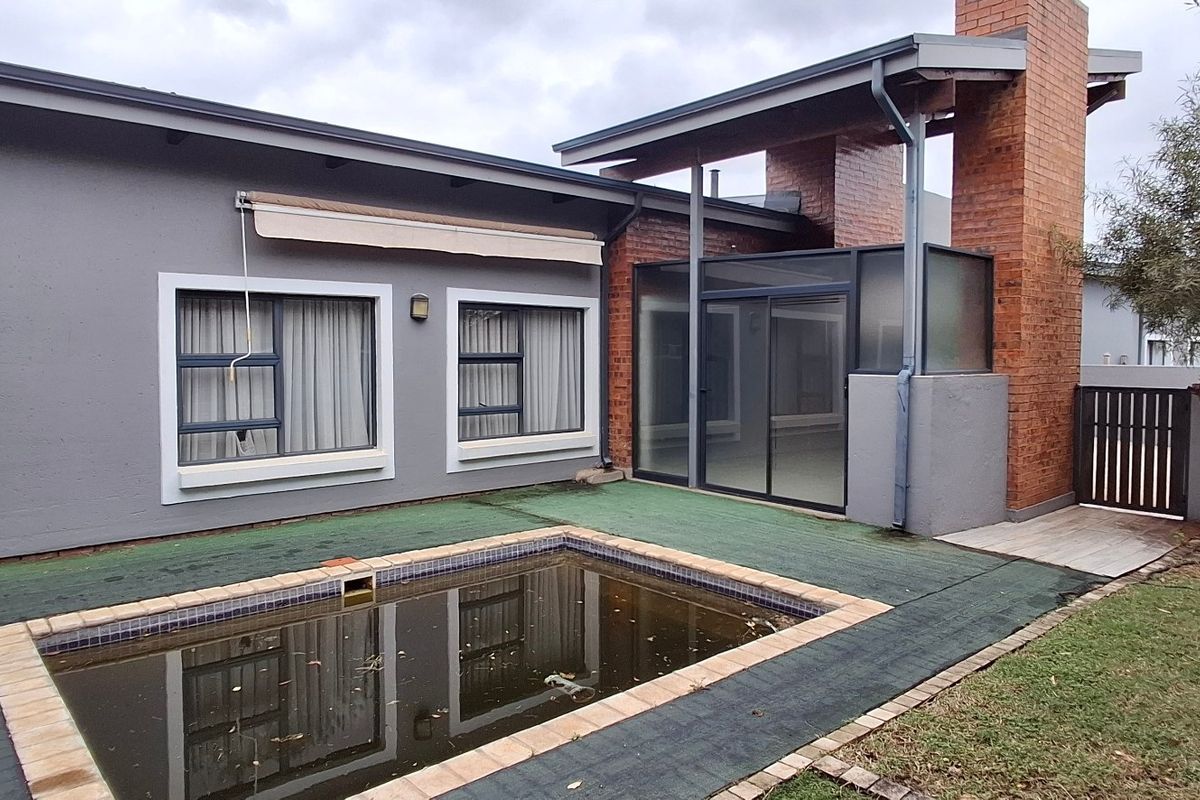 Rear exterior view of the townhouse featuring a swimming pool, brick chimney, and sliding glass doors leading to the living area.