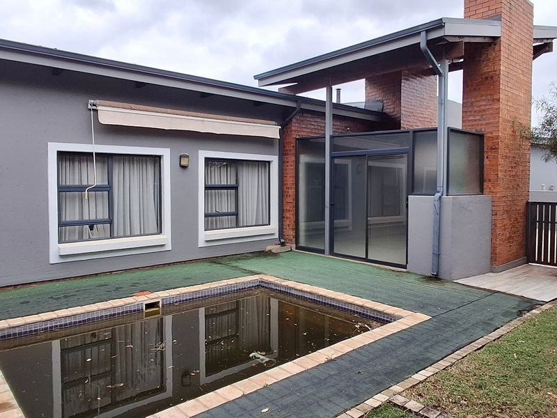 Rear exterior view of the townhouse featuring a swimming pool, brick chimney, and sliding glass doors leading to the living area.