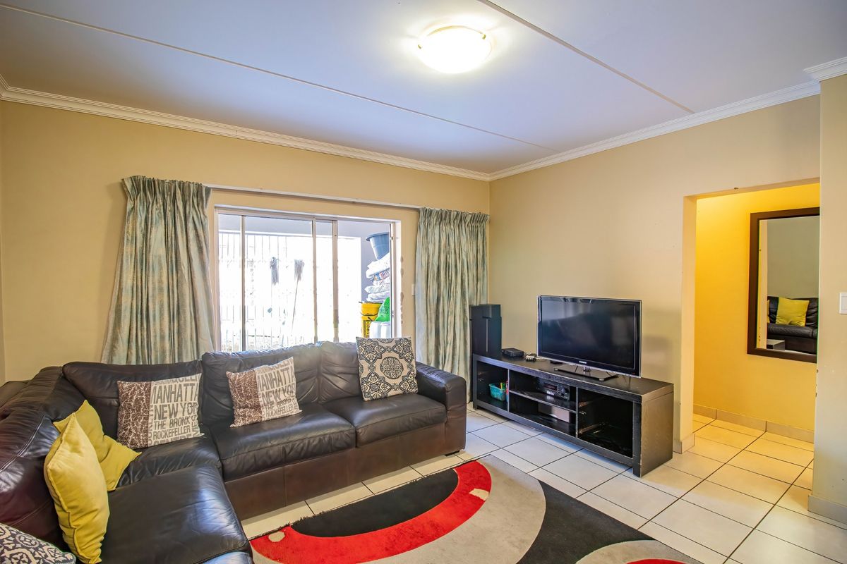 A living room featuring tiled flooring, coved ceilings, and a sliding glass door providing access to an outdoor area.