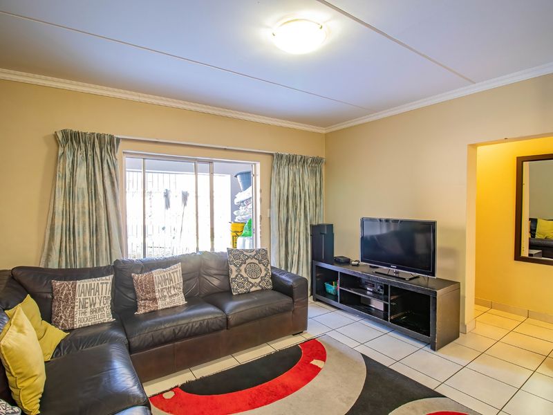 A living room featuring tiled flooring, coved ceilings, and a sliding glass door providing access to an outdoor area.