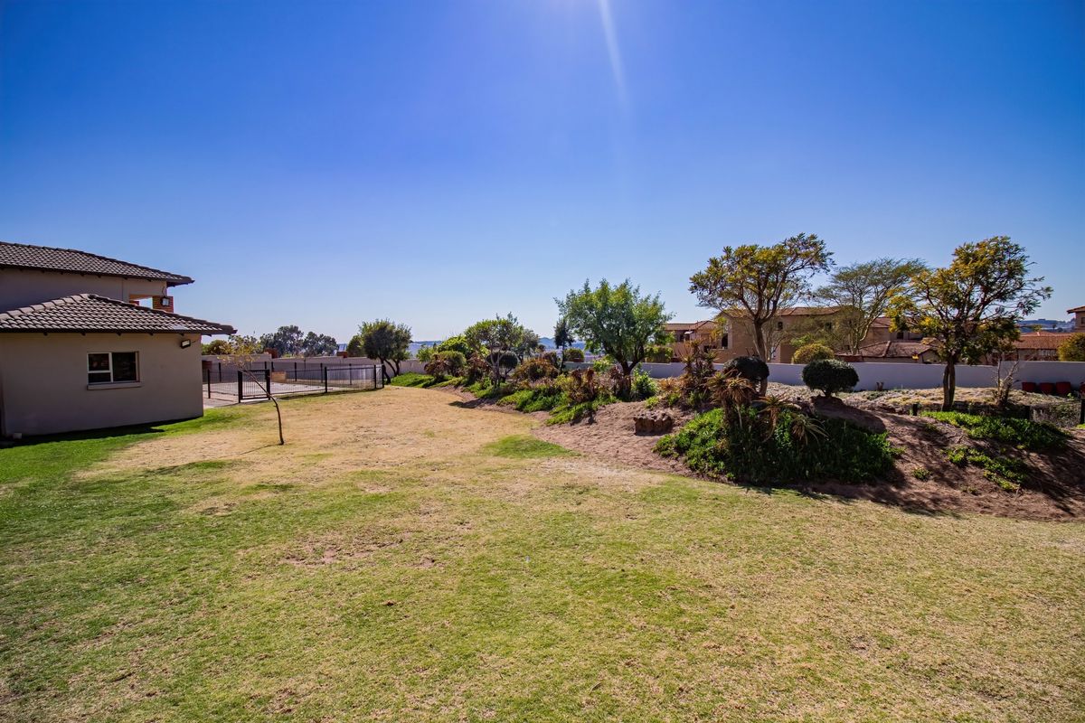 A spacious rear garden area featuring a lawn, landscaped garden beds, and a boundary wall, adjacent to the side elevation of the apartment building.