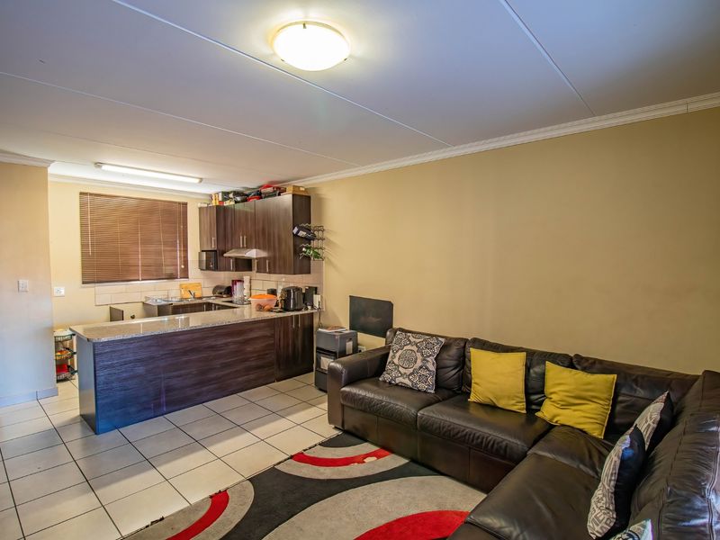 Open-plan living area featuring a kitchen with dark wood cabinetry, granite countertops, and tiled flooring, seamlessly flowing into the lounge space.