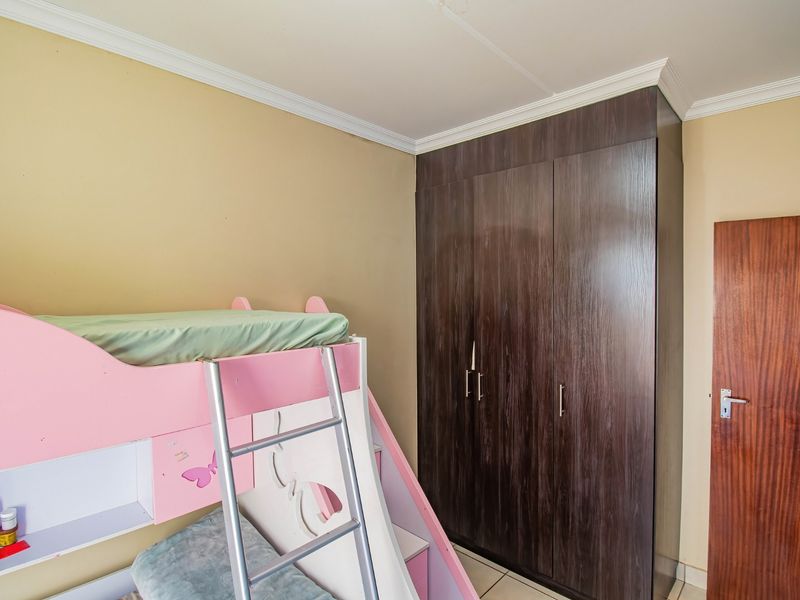 A bedroom featuring a dark wood built-in wardrobe, crown molding, and tiled flooring.