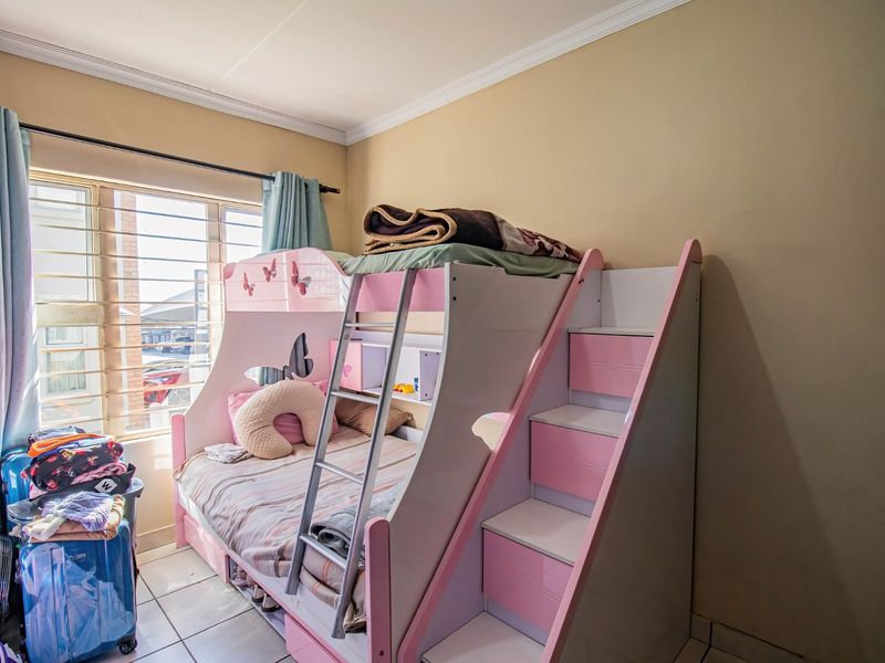 A bedroom featuring tiled flooring and security bars on the window, providing a functional space with natural light.