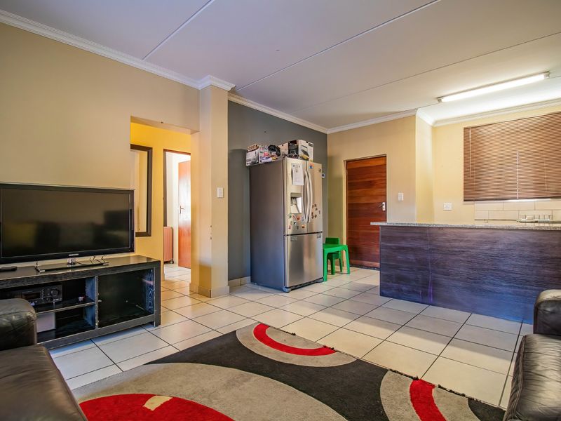 Open plan living and kitchen area featuring tiled flooring, a breakfast bar with granite countertop, and neutral wall finishes.