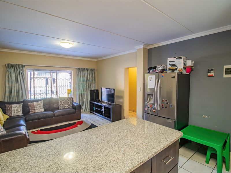 Open-plan living area featuring a granite-topped kitchen island, tiled flooring, and direct access to a secure patio area.