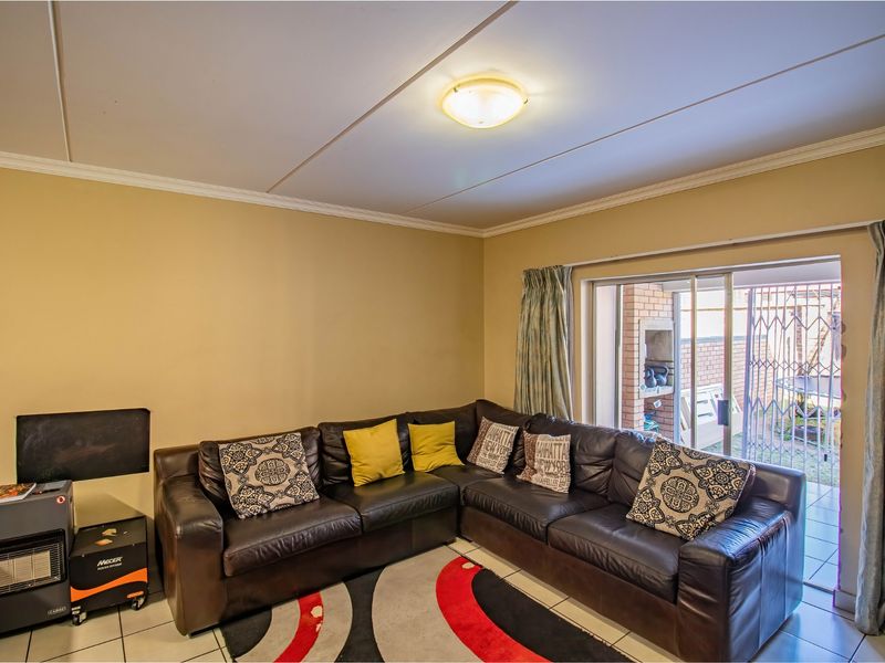 A living room featuring tiled flooring, ceiling cornice, and a sliding glass door providing access to an outdoor patio area.
