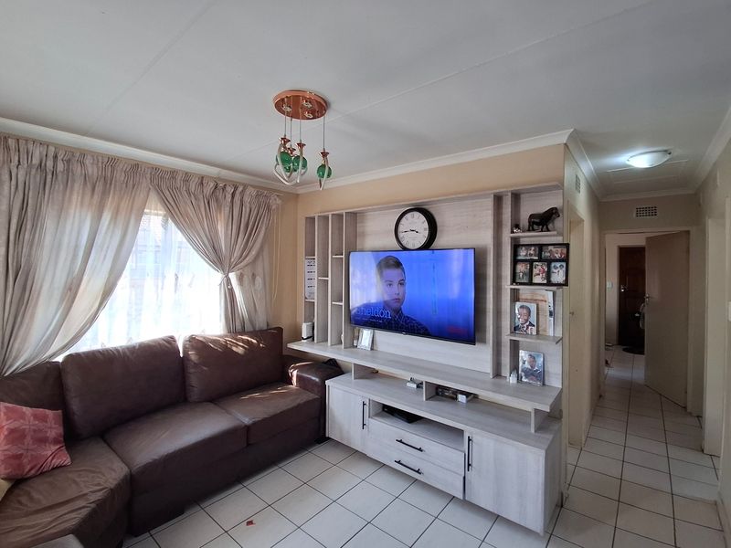 A living room featuring a built-in media unit, tiled flooring, and neutral wall finishes, providing a functional space for entertainment.
