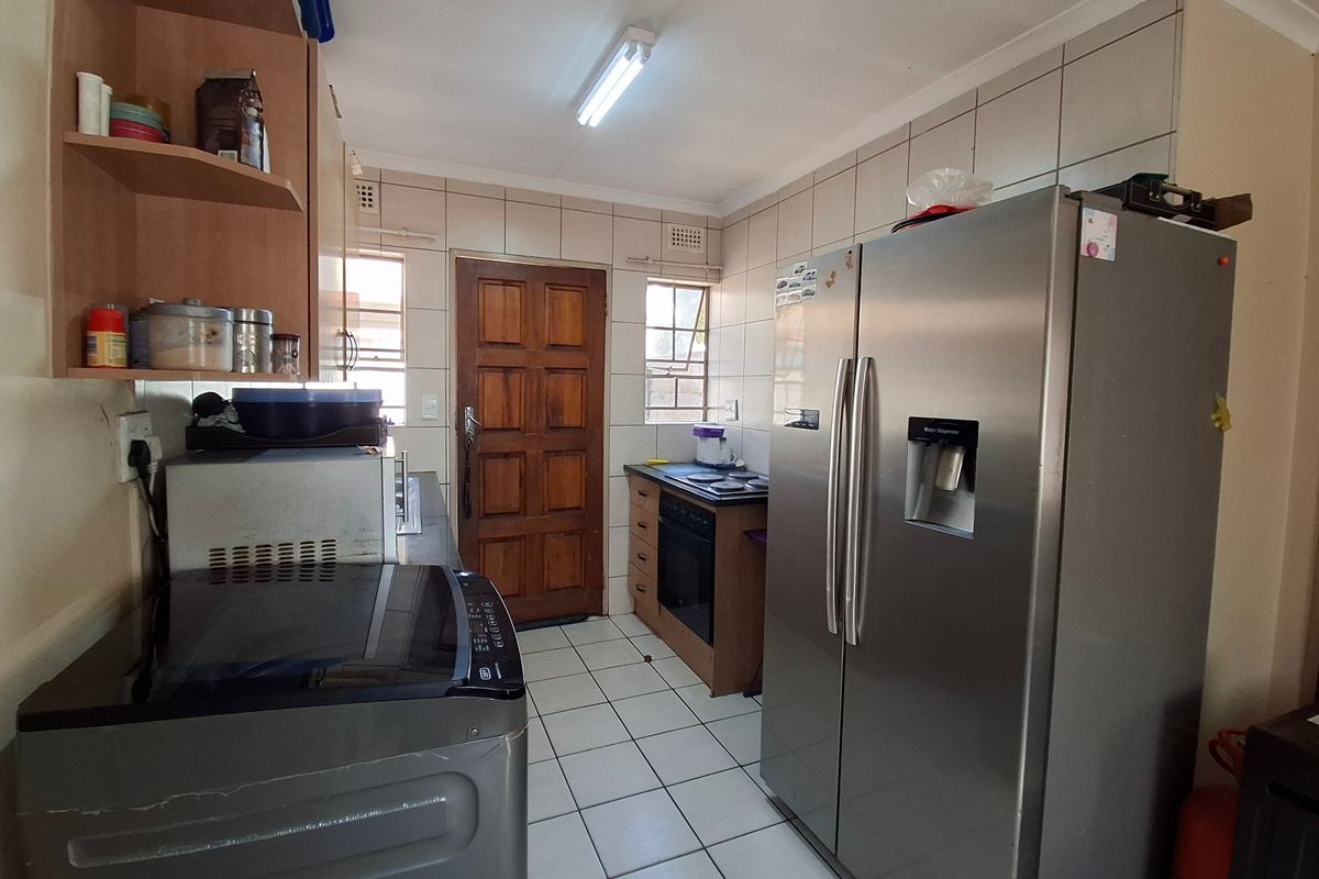 Functional kitchen featuring tiled flooring, built-in cabinetry, and integrated oven and hob, offering a practical layout with direct exterior access.