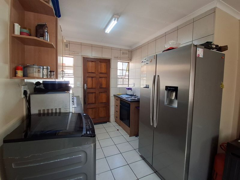 Functional kitchen featuring tiled flooring, built-in cabinetry, and integrated oven and hob, offering a practical layout with direct exterior access.