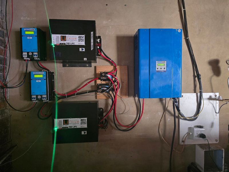 Wall-mounted solar power system featuring two lithium battery units, two MPPT charge controllers, and a central inverter for off-grid energy management.