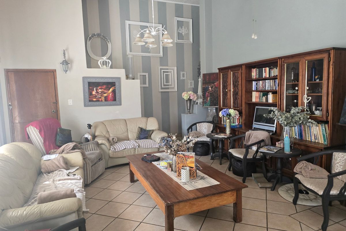 Spacious living room featuring tiled flooring, vaulted ceilings, and built-in wooden cabinetry, offering a comfortable and traditional living space.
