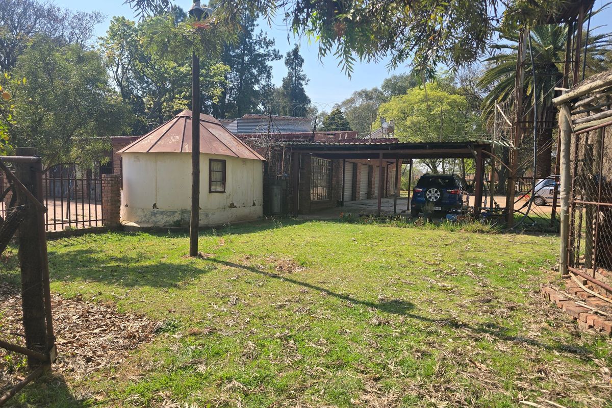 Rear garden area featuring a carport, a small circular outbuilding, and a water tank stand on a farm property.