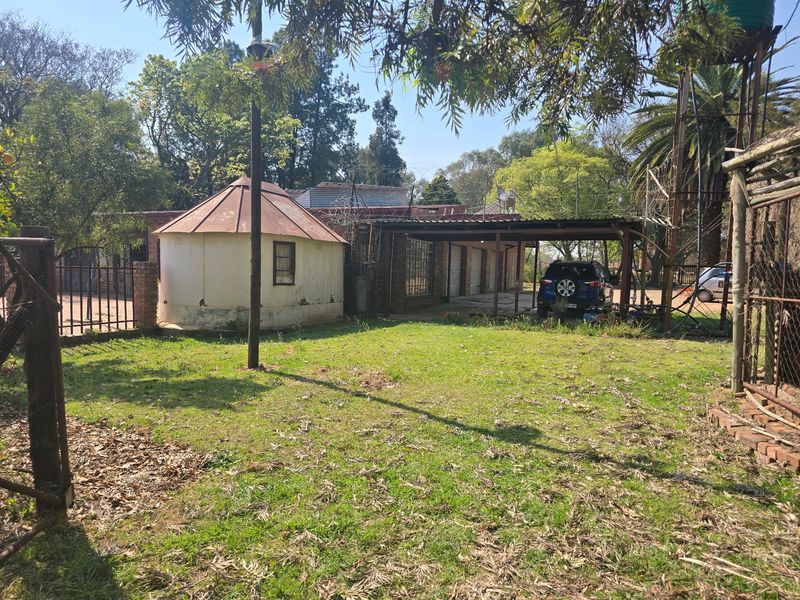 Rear garden area featuring a carport, a small circular outbuilding, and a water tank stand on a farm property.
