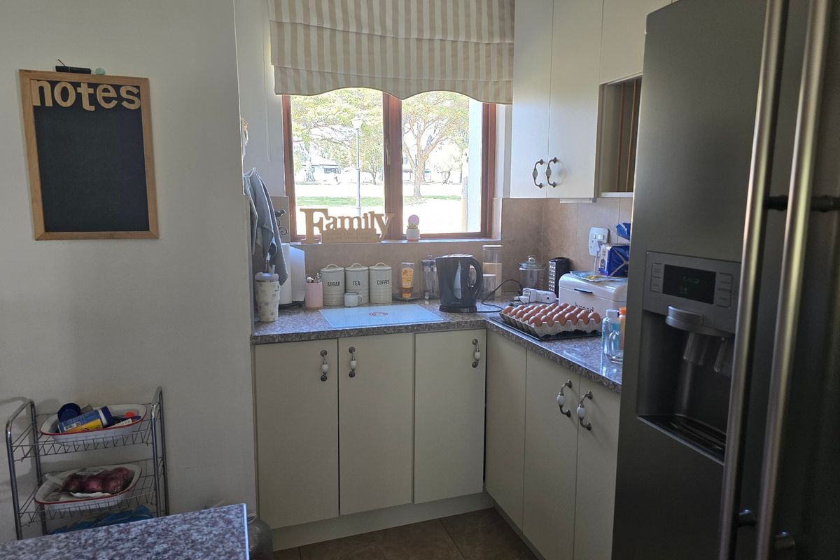 A functional kitchen area featuring built-in cabinetry, laminate countertops, and tiled flooring, with natural light provided by a window overlooking the exterior.