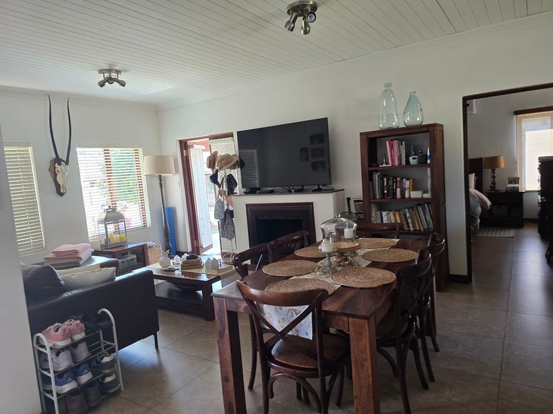 Open plan living and dining area featuring tiled flooring, a built-in fireplace, and a white tongue and groove ceiling with spotlight fixtures.