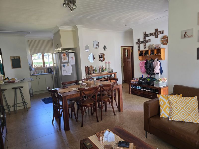 Open-plan living and dining area featuring tiled floors, a tongue and groove ceiling, and a functional kitchen with granite countertops and a breakfast bar.