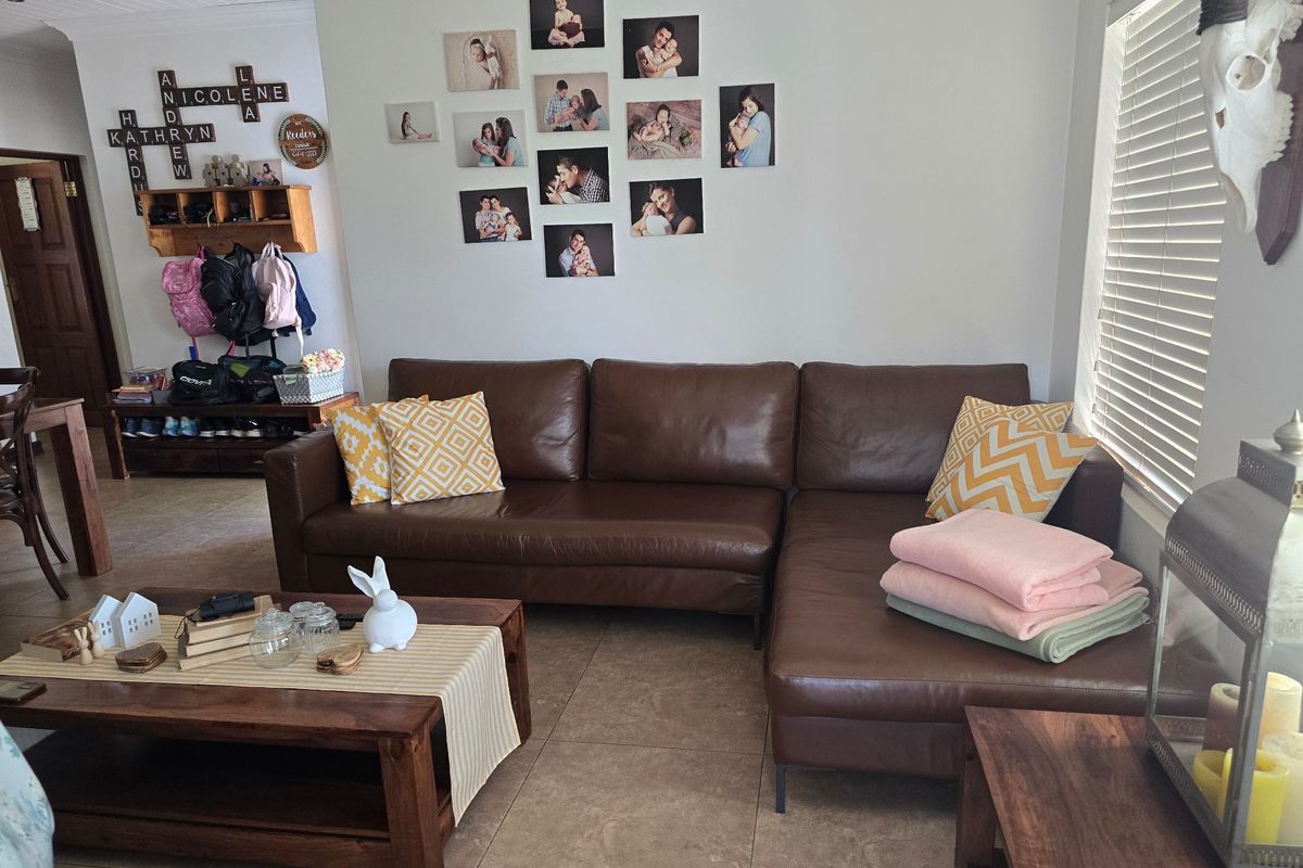 A comfortable living room featuring neutral tiled flooring, natural light through venetian blinds, and a functional built-in storage area.