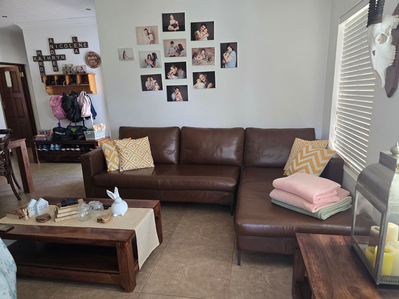 A comfortable living room featuring neutral tiled flooring, natural light through venetian blinds, and a functional built-in storage area.