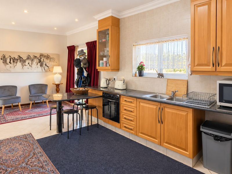 Open-plan kitchen and living area featuring wooden cabinetry, laminate countertops, tiled backsplash, and integrated oven, creating a functional and connected living space.